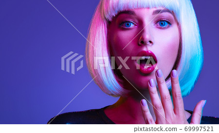 Surprised  Face of glamour girl. Wondered female face in a white wig. Young beautiful woman with a shocked face. Art portrait  of  an young attractive woman with hands at face. Emotional person. 69997521