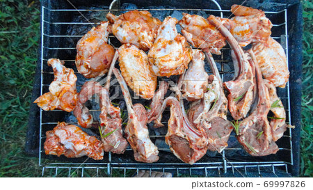 Chicken wings on barbecue grill with fire close up. Chicken meat on the grill Chicken wings on barbecue grill with fire close up. Chicken meat on the grill 69997826