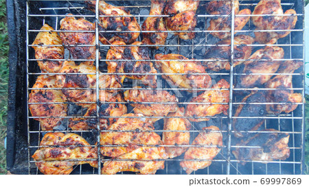Chicken wings on barbecue grill with fire close up. Chicken meat on the grill 69997869