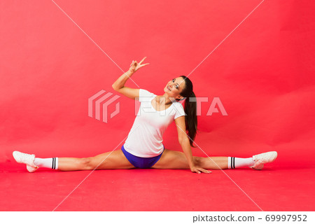 Beautiful cool young fit gymnast woman in sportswear working out, gymnastics element, doing split Beautiful cool young fit gymnast woman in sportswear working out, gymnastics element, doing split 69997952