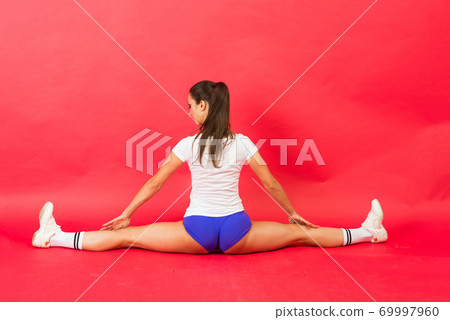 Beautiful cool young fit gymnast woman in sportswear working out, gymnastics element, doing split Beautiful cool young fit gymnast woman in sportswear working out, gymnastics element, doing split 69997960