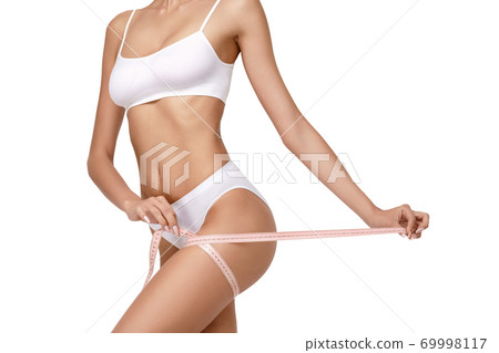 Slim tanned woman's body over gray background - waist measurement 69998117