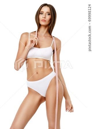 Slim tanned woman's body over gray background - waist measurement 69998124