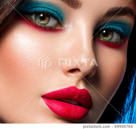 Portrait of beautiful young woman with bright blue makeup. Beautiful brunette with bright red lipstick on her lips. Pretty girl with long black hair. Closeup face of brunette woman. Sexy girl. Portrait of beautiful young woman with bright blue makeup. Beautiful brunette with bright red lipstick on her lips. Pretty girl with long black hair. Closeup face of brunette woman. Sexy girl. 69998768