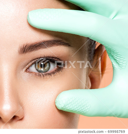 Face skin check before plastic surgery. Beautician touching young woman face. Doctor in medicine gloves checks a skin before plastic surgery. Beauty treatments. Face skin check before plastic surgery. Beautician touching young woman face. Doctor in medicine gloves checks a skin before plastic surgery. Beauty treatments. 69998769