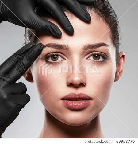 Face skin check before plastic surgery. Beautician touching woman face. Doctor checks a skin before plastic surgery. Beauty treatments. Plastic surgery doctor is touching face of a patient by hands Face skin check before plastic surgery. Beautician touching woman face. Doctor checks a skin before plastic surgery. Beauty treatments. Plastic surgery doctor is touching face of a patient by hands 69998770