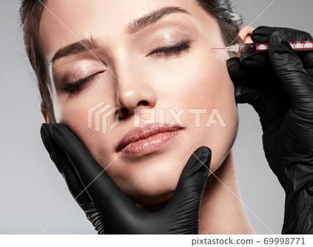 Caucasian woman getting botox cosmetic injection in forehead. Woman gets botox injection in her face Caucasian woman getting botox cosmetic injection in forehead. Woman gets botox injection in her face 69998771