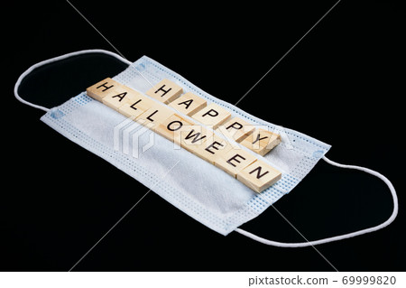 Medical mask and wooden words Happy Halloween on black background. Halloween background decor holiday concept Medical mask and wooden words Happy Halloween on black background. Halloween background decor holiday concept 69999820