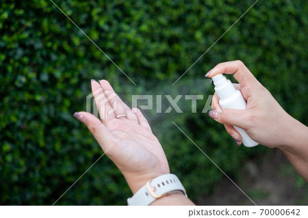 woman or girl applying spray disinfection alcohol product on hand 70000642