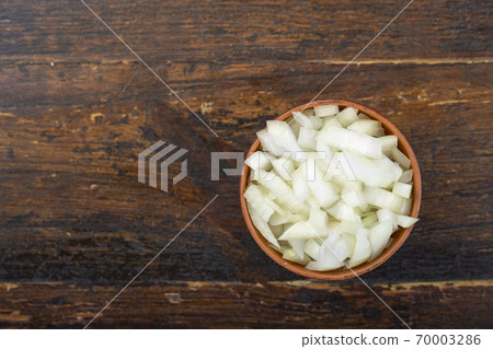 Sliced raw onion in a bowl on a wooden background. Vegetable, ingredient and staple food. 70003286