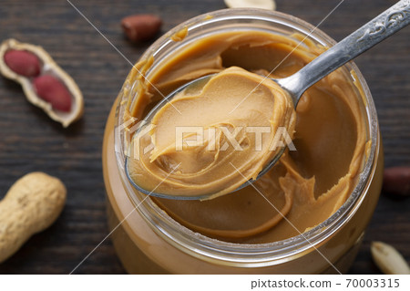 peanut paste in an open jar and peanuts in the peel 70003315