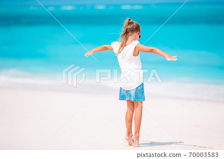 Adorable active little girl at beach during summer vacation Adorable active little girl at beach during summer vacation 70003583