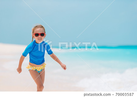 Adorable active little girl at beach during summer vacation Adorable active little girl at beach during summer vacation 70003587