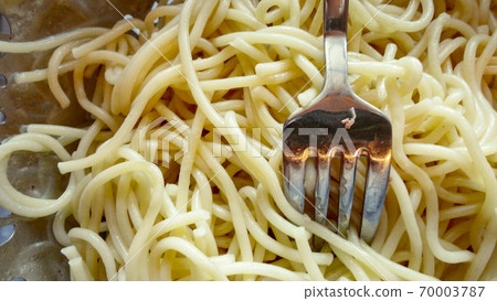 Large bowl with freshly cooked pasta spaghetti and metal fork closeup 70003787