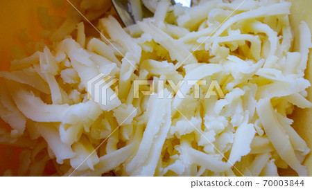Grated Cheddar Cheese on rustic yellow background with metal fork 70003844
