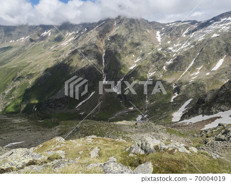 view from Niederl saddle on Nurnberger Hutte mountain hut and snow-capped peaks at Stubai hiking trail, Stubai Hohenweg, Summer rocky alpine landscape of Tyrol, Stubai Alps, Austria 70004019