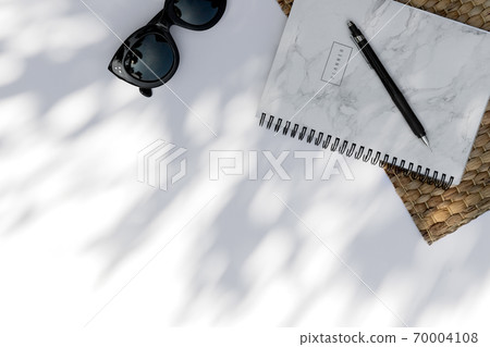 Trendy sunglasses, planner with palm leaf shadow on white background Trendy sunglasses, planner with palm leaf shadow on white background 70004108