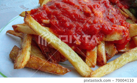 french fries covered with hot organic  tomato sauce closeup in the white plate french fries covered with hot organic  tomato sauce closeup in the white plate 70004110