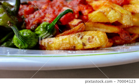 french fries covered with hot organic  tomato sauce closeup in the white plate 70004123