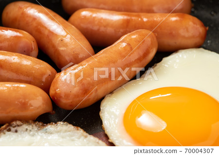 Wiener sausage and fried egg baked in a frying pan. 70004307