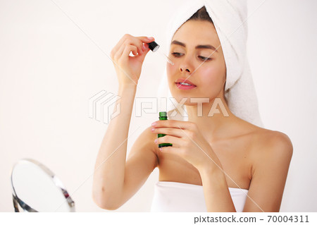 beautiful young brunette woman applying gel on her eyebrows 70004311