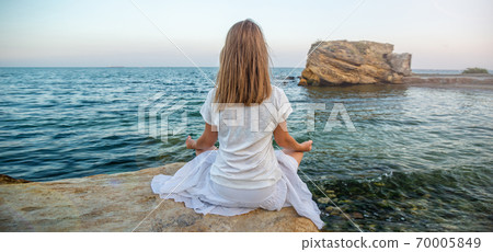 Woman meditating at the sea Woman meditating at the sea 70005849