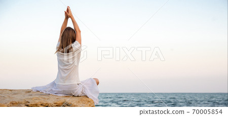 Woman meditating at the sea 70005854