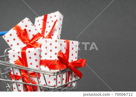 Grocery cart full of gifts on a dark gray background with place for copy space. Black Friday and holidays concept. Grocery cart full of gifts on a dark gray background with place for copy space. Black Friday and holidays concept. 70006712
