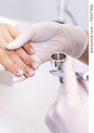 Woman receiving manicure by airbrush Woman receiving manicure by airbrush 70007900