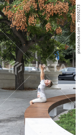 Boy pulls two hands up to the branches of the tree. Soap tree in an urban environment. 70008273
