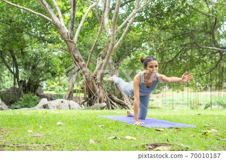 Portrait of a young woman doing yoga in the garden for a workout. Concept of lifestyle fitness and healthy. Asian women are practicing yoga in the park. Portrait of a young woman doing yoga in the garden for a workout. Concept of lifestyle fitness and healthy. Asian women are practicing yoga in the park. 70010187