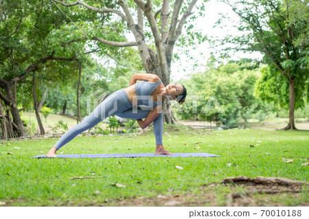 Portrait of a young woman doing yoga in the garden for a workout. Concept of lifestyle fitness and healthy. Asian women are practicing yoga in the park. Portrait of a young woman doing yoga in the garden for a workout. Concept of lifestyle fitness and healthy. Asian women are practicing yoga in the park. 70010188