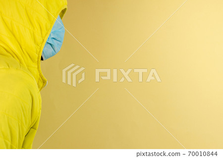 man in yellow jacket is using a protective mask against corona virus on yellow background man in yellow jacket is using a protective mask against corona virus on yellow background 70010844