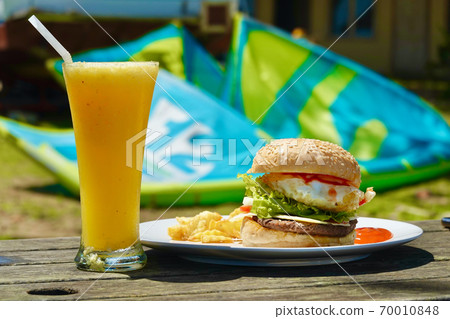 Hamburger and orange juice @ kitesurfing beach Hamburger and orange juice @ kitesurfing beach 70010848