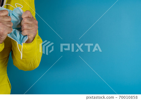 man in yellow jacket is using a protective mask against corona virus on blue background 70010858