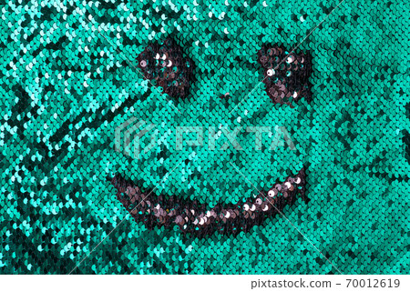 Fabric sequins background of turquoise color with smiling face. 70012619