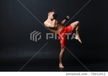 Sportsman muay thai man boxer stance ad knee kick at black background Sportsman muay thai man boxer stance ad knee kick at black background 70012812