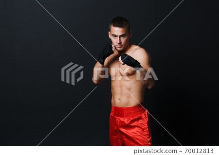 Sportsman muay thai man boxer stance in red truncks at black background Sportsman muay thai man boxer stance in red truncks at black background 70012813