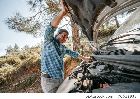 Man is looking to open car hood for trouble car. Transportation and vehicle concept. Man is looking to open car hood for trouble car. Transportation and vehicle concept. 70012933