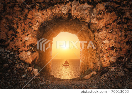 A nice view from a antique historical castle to the sea with a sailboat against sunset. A nice view from a antique historical castle to the sea with a sailboat against sunset. 70013003