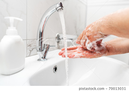 Personal hygiene, cleaning hands with soap often on faucet to protect from virus. 70013031
