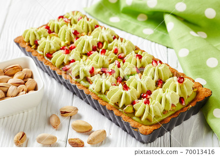 Pistachio ganache tart on a white wooden table Pistachio ganache tart on a white wooden table 70013416