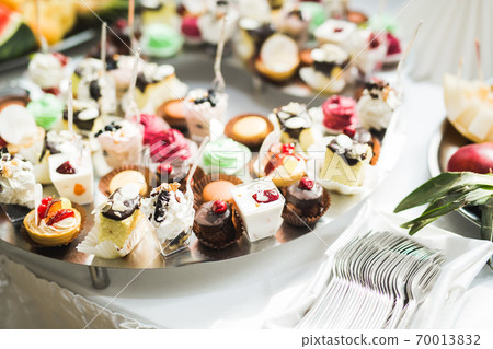 Delicious and tasty dessert table with cupcakes shots at reception closeup 70013832