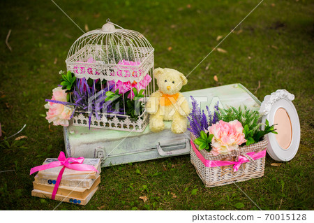street decorations for a children's party. Retro suitcase with flowers with a teddy bear in a green park. Party on the street 70015128