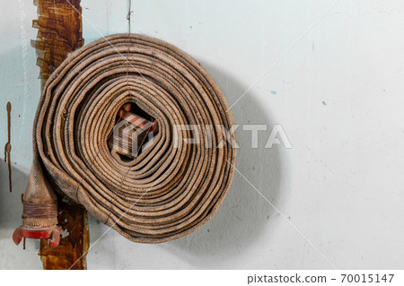 Twisted old rusty fire hydrant hose. Poor fire safety in the building Twisted old rusty fire hydrant hose. Poor fire safety in the building 70015147