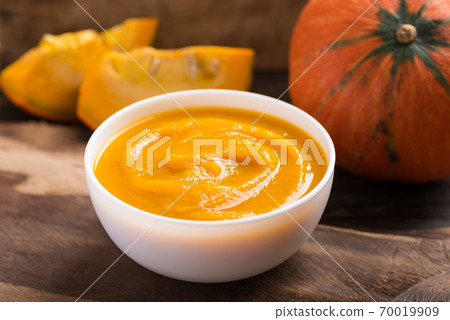 Pumpkin soup in a bowl on wooden background Pumpkin soup in a bowl on wooden background 70019909