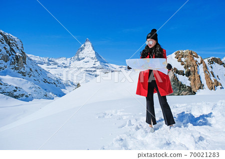 Young female looking map at Matterhorn in Switzerland with panoramic view of the Swiss Skyline. Young female looking map at Matterhorn in Switzerland with panoramic view of the Swiss Skyline. 70021283