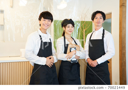 A clerk standing in front of a cash register in a cafe with a vinyl partition A clerk standing in front of a cash register in a cafe with a vinyl partition 70021449