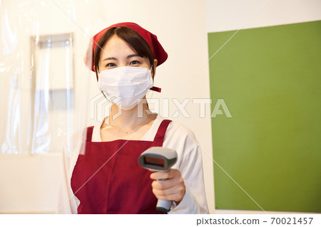 A clerk standing in a store with a vinyl partition 70021457