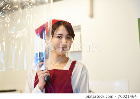 A clerk standing in a store with a vinyl partition 70021464